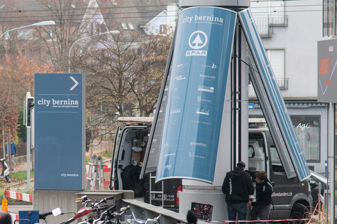 Der Pylon für City Bernina wird mit einem Kran aufgestellt. Flügeltüren nach oben öffnend