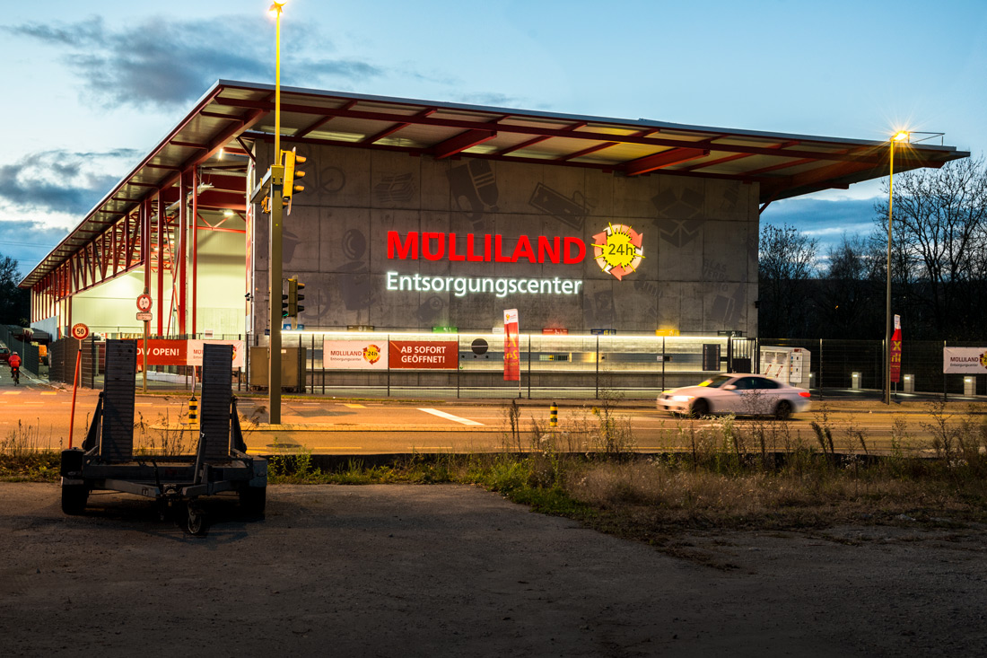 Leuchtschrift Fassade Muelliland-Entsorgungscenter: 13x4 Meter, in der Daemmerung, mit leuchtender Sonne mit natuerlichem Lichteffekt