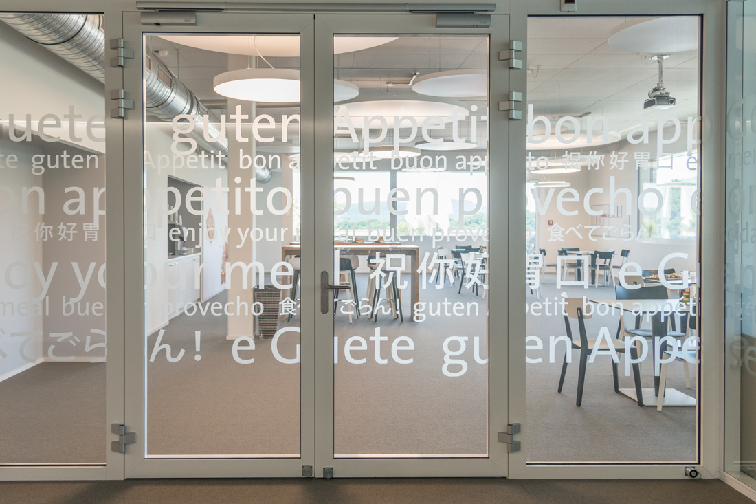 Office Branding der Cafeteria im Laeckerli Huus: Transparentfolien auf Glas mit Aufschriften: En Guete in verschiedenen Sprachen