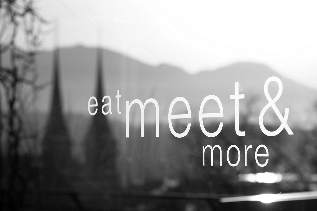 Wandfolie mit Schwarz-Weiss-Motiv als Hintergrund fuer den Slogan: eat meet and more