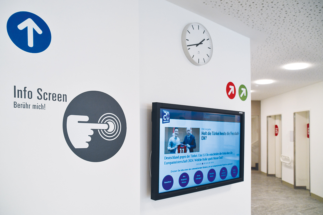 Signaletik Alters- Pflegeheim: Infowand mit Display, Uhr, Info Screen und Pfeilen